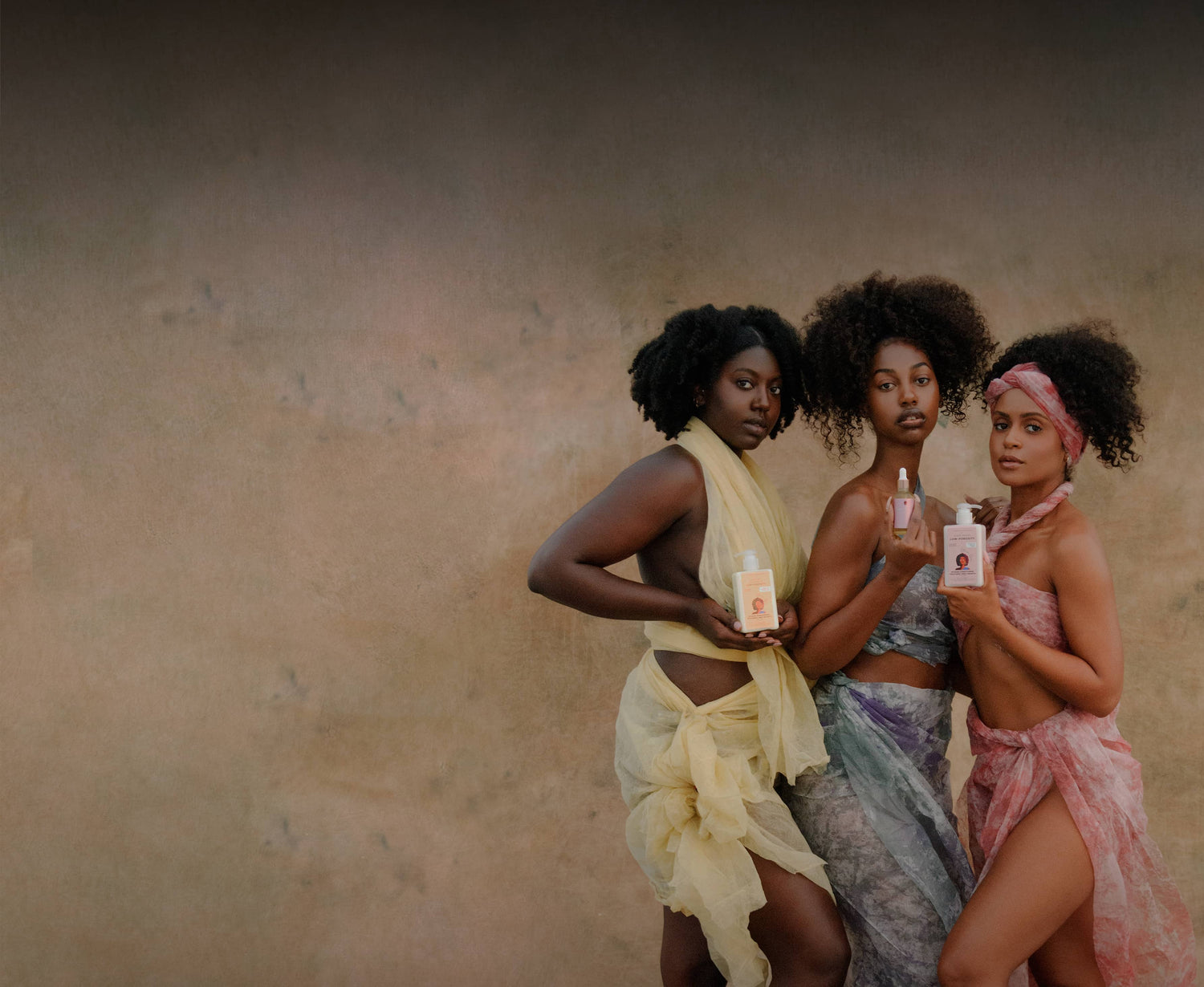 Three women holding low porosity products against a neutral background