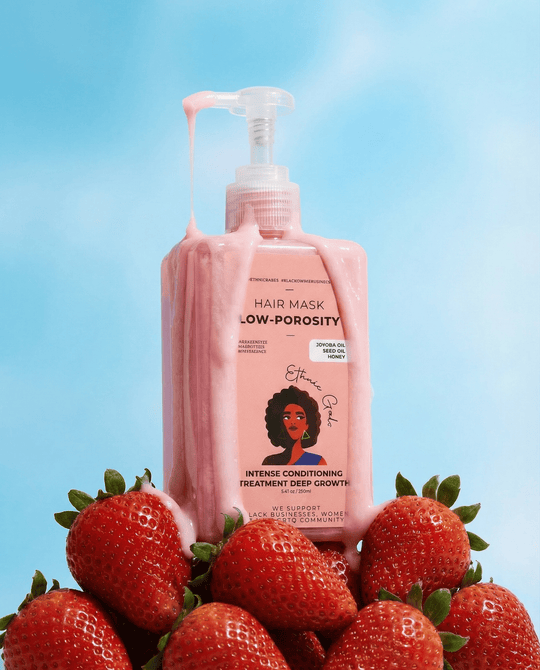 Pink hair mask bottle with pump dispenser on strawberries against a blue background