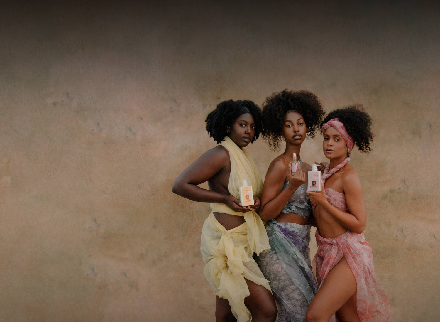 Three women holding low porosity products against a neutral background