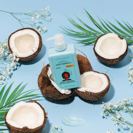 Shampoo bottle on halved coconuts with green leaves and flowers on a blue background