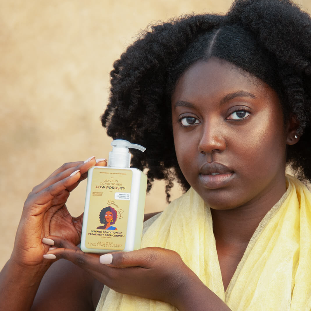 Woman holding a bottle of hair care product with a neutral background