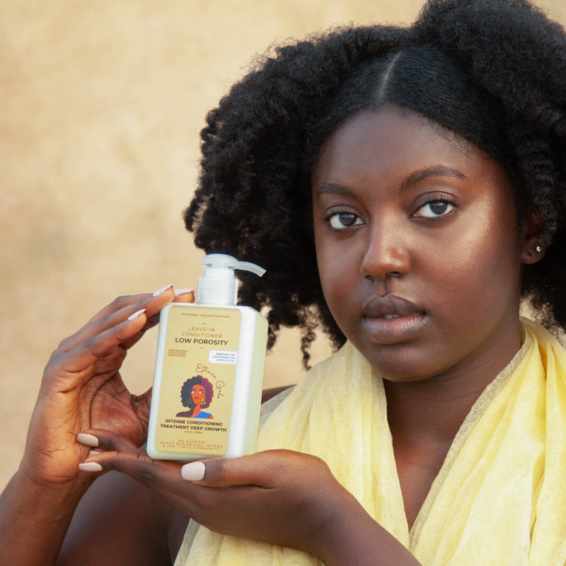 Woman holding a bottle of hair care product with a neutral background