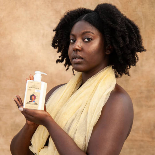 Woman holding a bottle of shampoo against a beige background